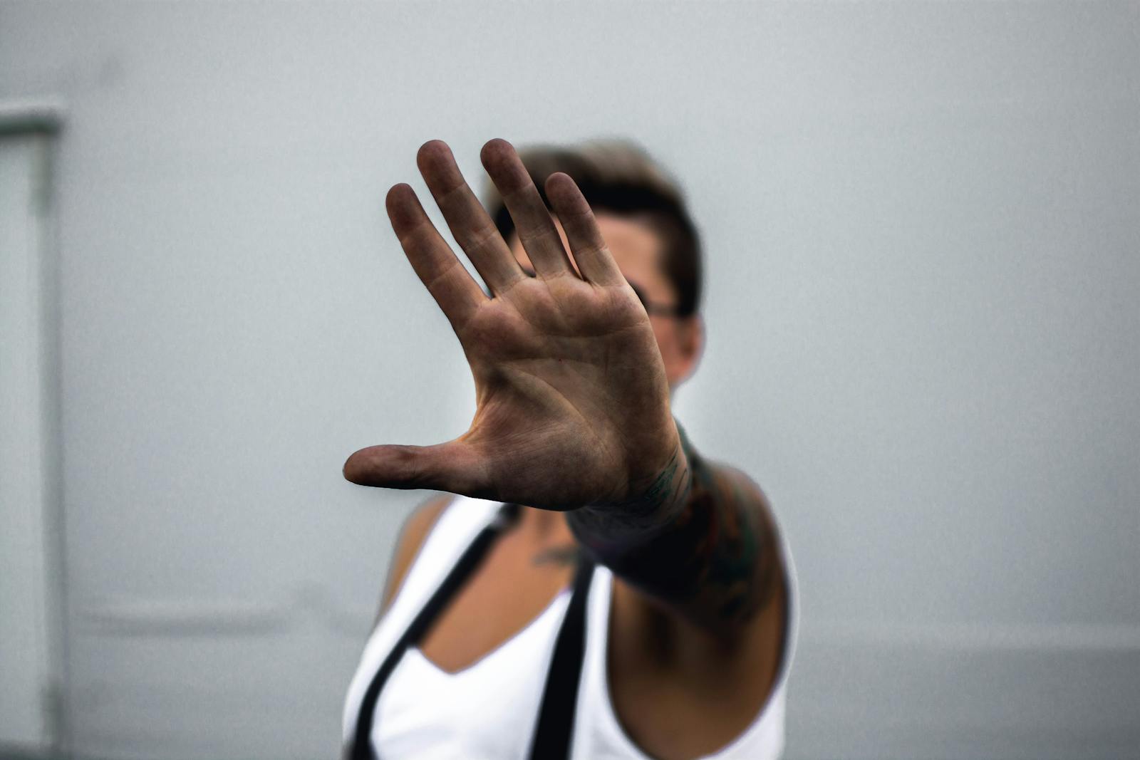 Photo by lil artsy Close-up of a person's hand raised in a stop gesture, against a neutral background.