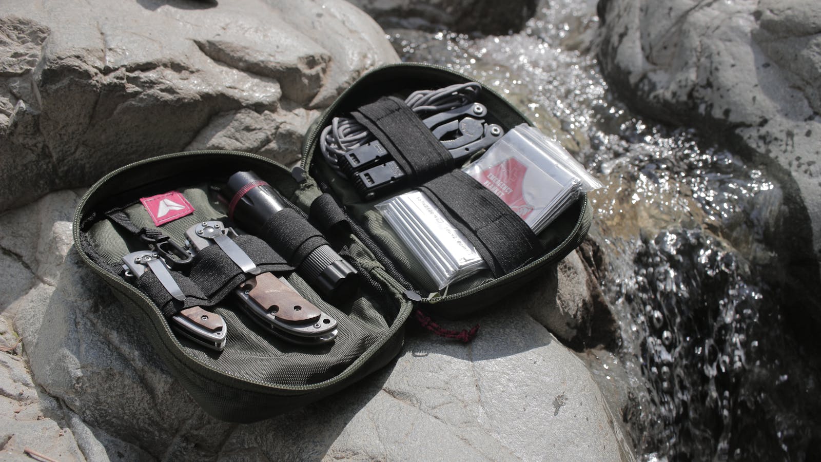 Photo by Baihaki Hine High-quality outdoor survival kit displayed on rocks near a flowing stream