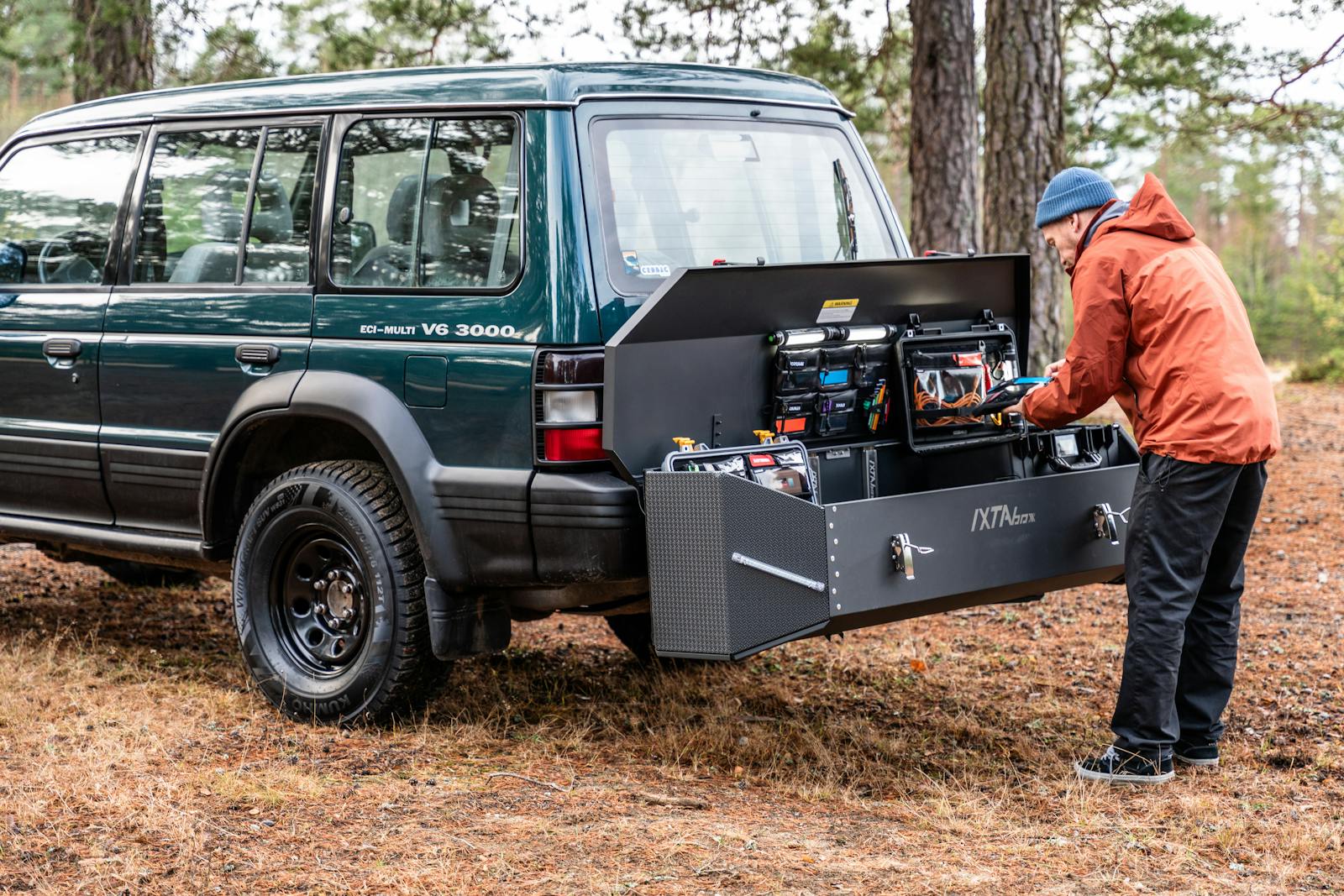 Photo by Andreas Näslund A rugged vehicle with a versatile storage solution in a forest setting, ideal for outdoor adventures.