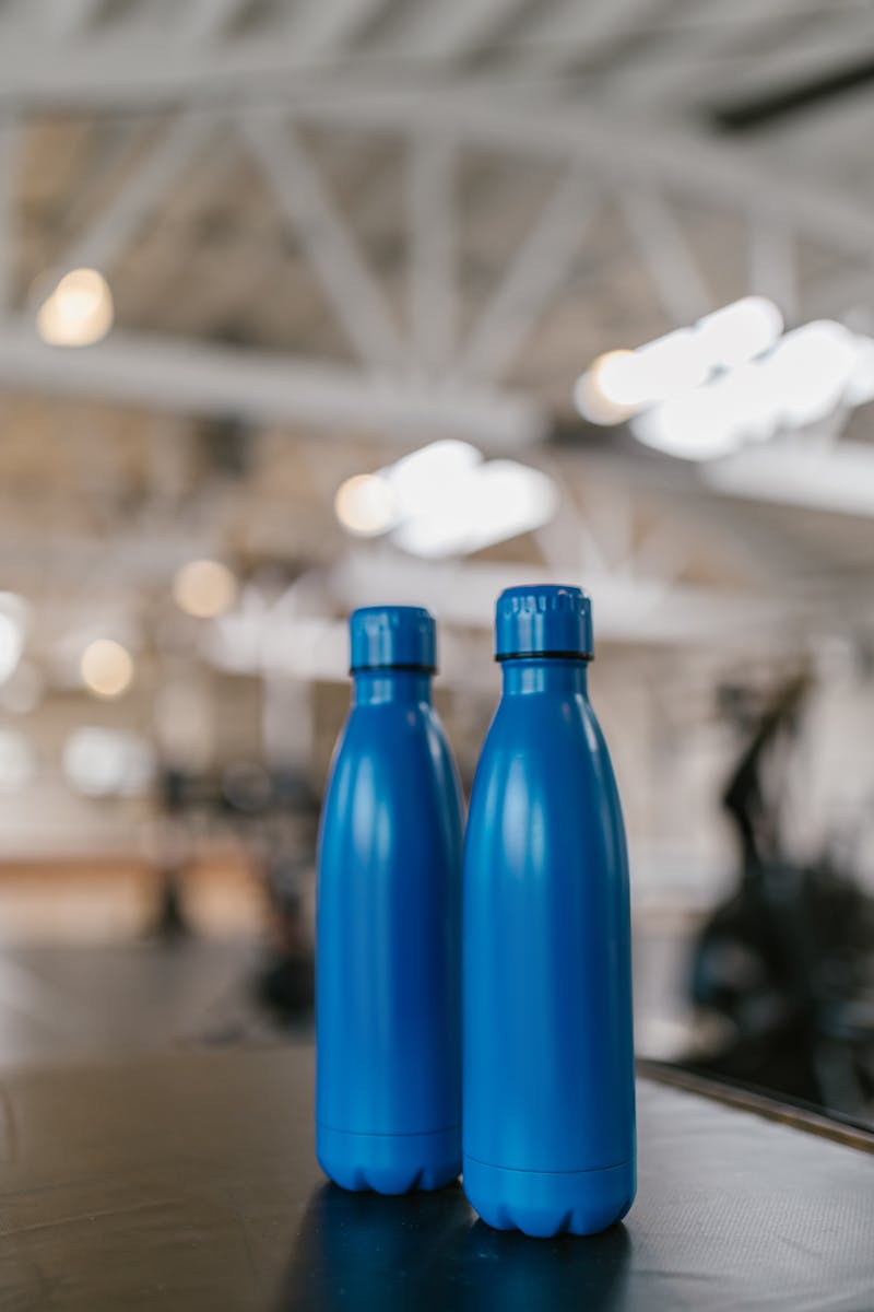 Photo by RDNE Stock project Close-up of two blue water bottles against a blurred indoor background.