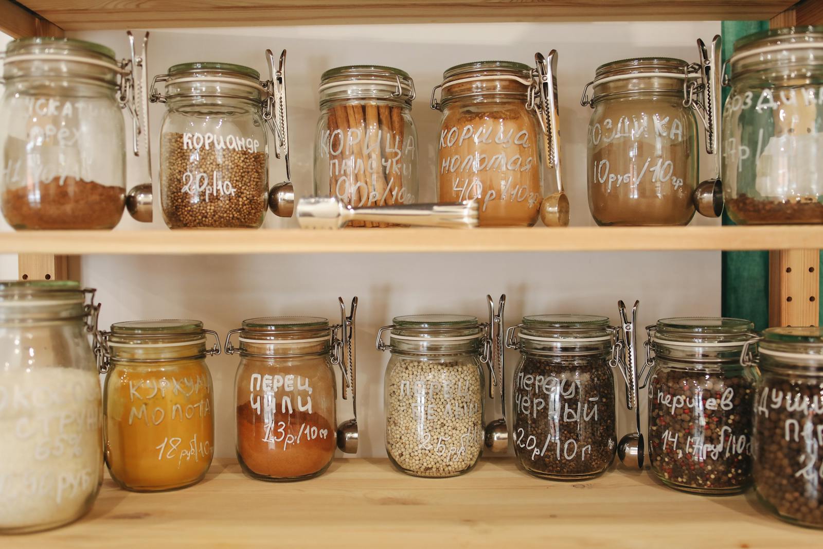 Photo by Polina Tankilevitch Organized pantry with glass jars holding a variety of spices and ingredients on wooden shelves.