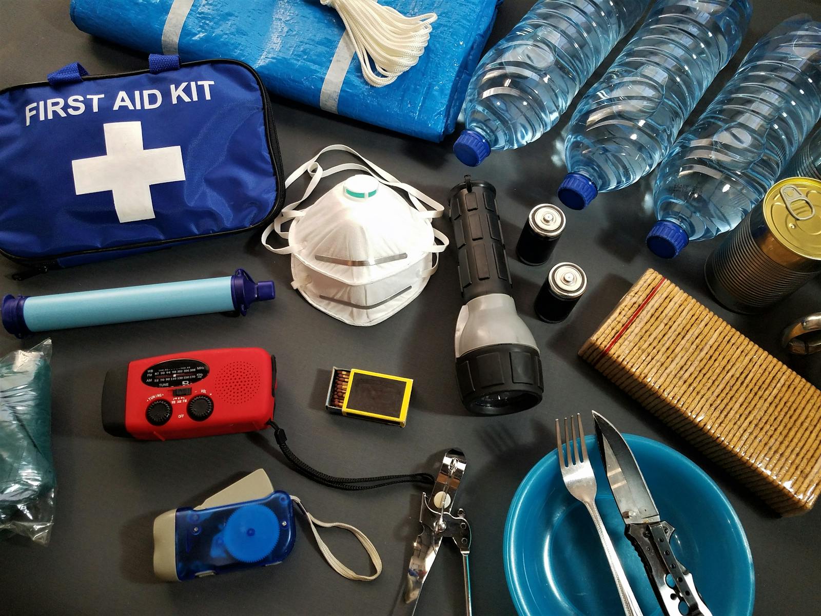 Photo by Roger Brown Flat lay of essential emergency survival kit items including first aid and water bottles.