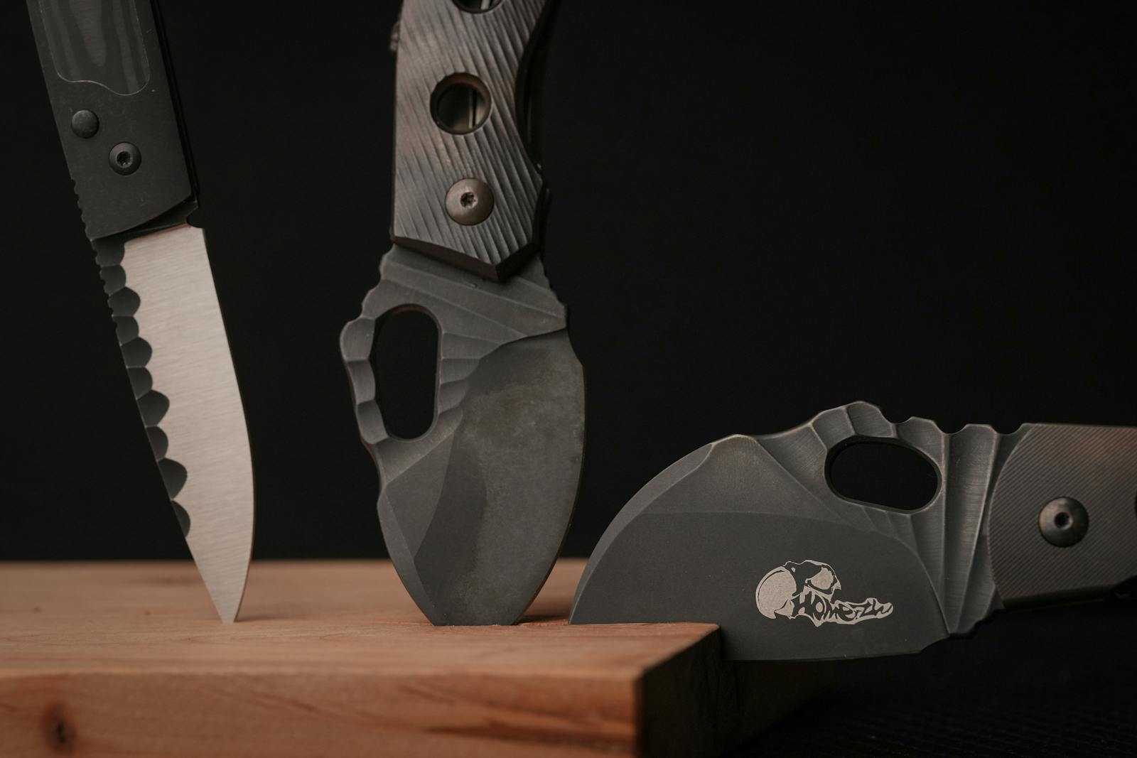 Photo by ha ha A sharp and sleek display of three modern tactical knives set against a dark background.