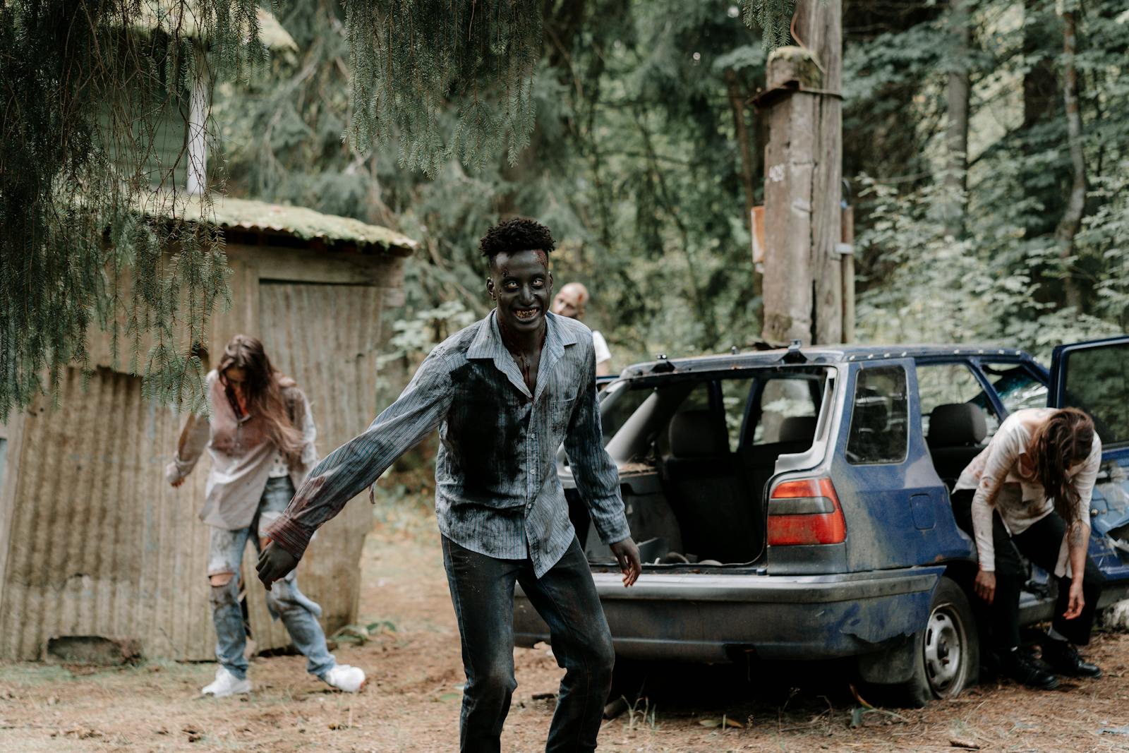 Photo by cottonbro studio Zombies wander through a forest near an abandoned car, creating a terrifying atmosphere.