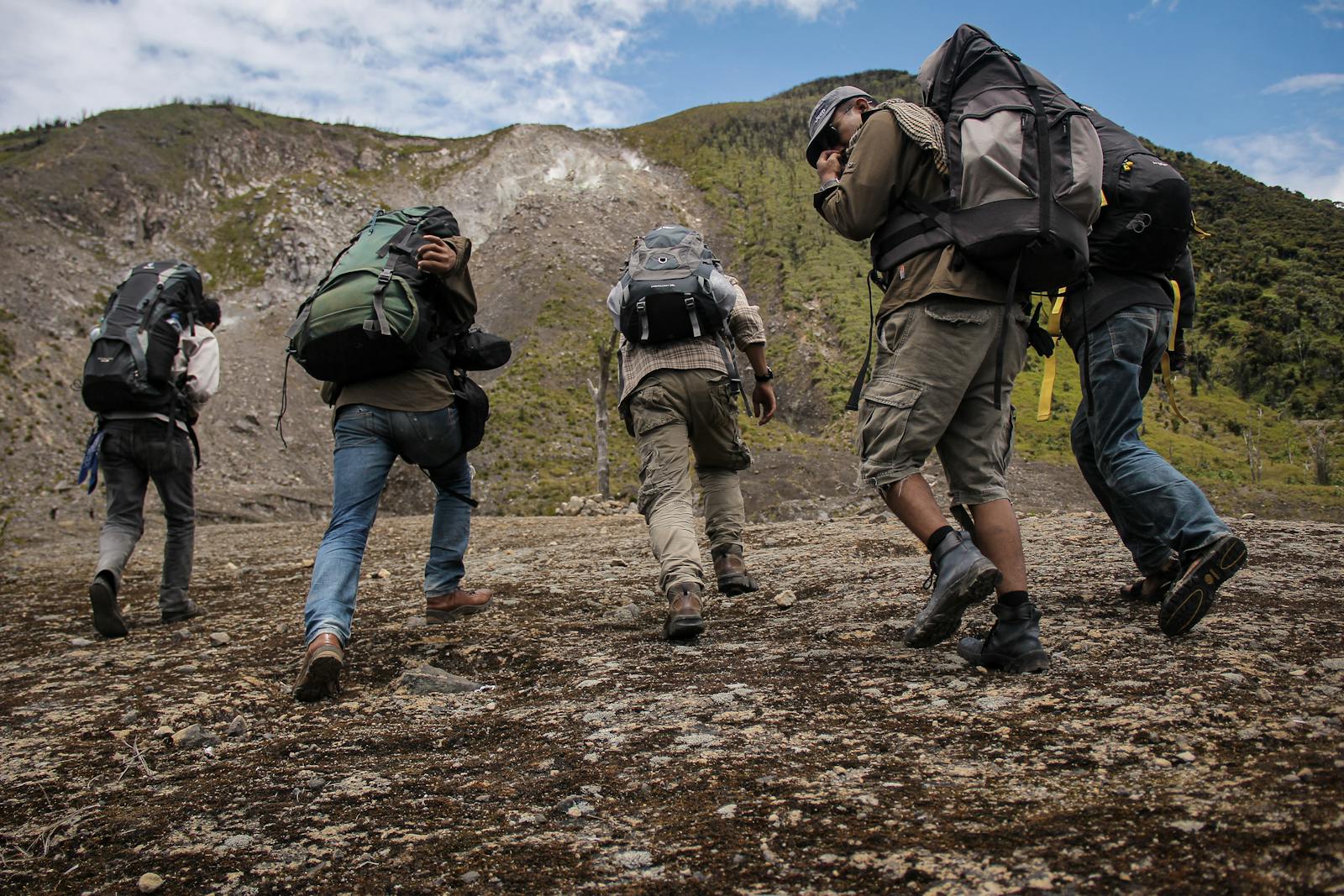 Photo by Nans 82 Five hikers with backpacks trekking up a mountain path in West Sumatra, Indonesia.