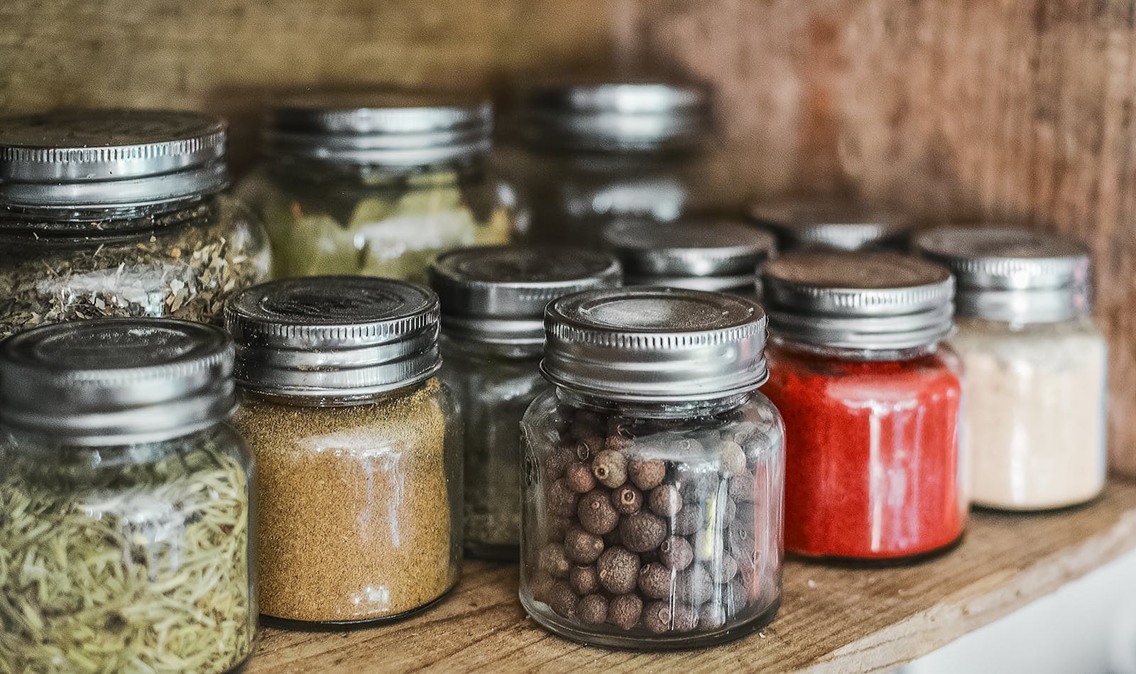 Photo by Pixabay Close-up of assorted spice jars with various herbs on a kitchen shelf, showcasing colorful culinary ingredients.