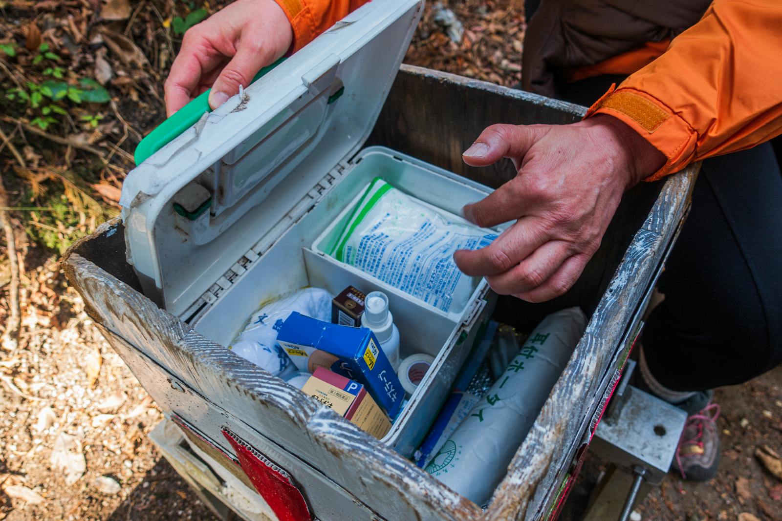 A hiker opens a first aid kit during an outdoor adventure in Dazaifu, Japan.