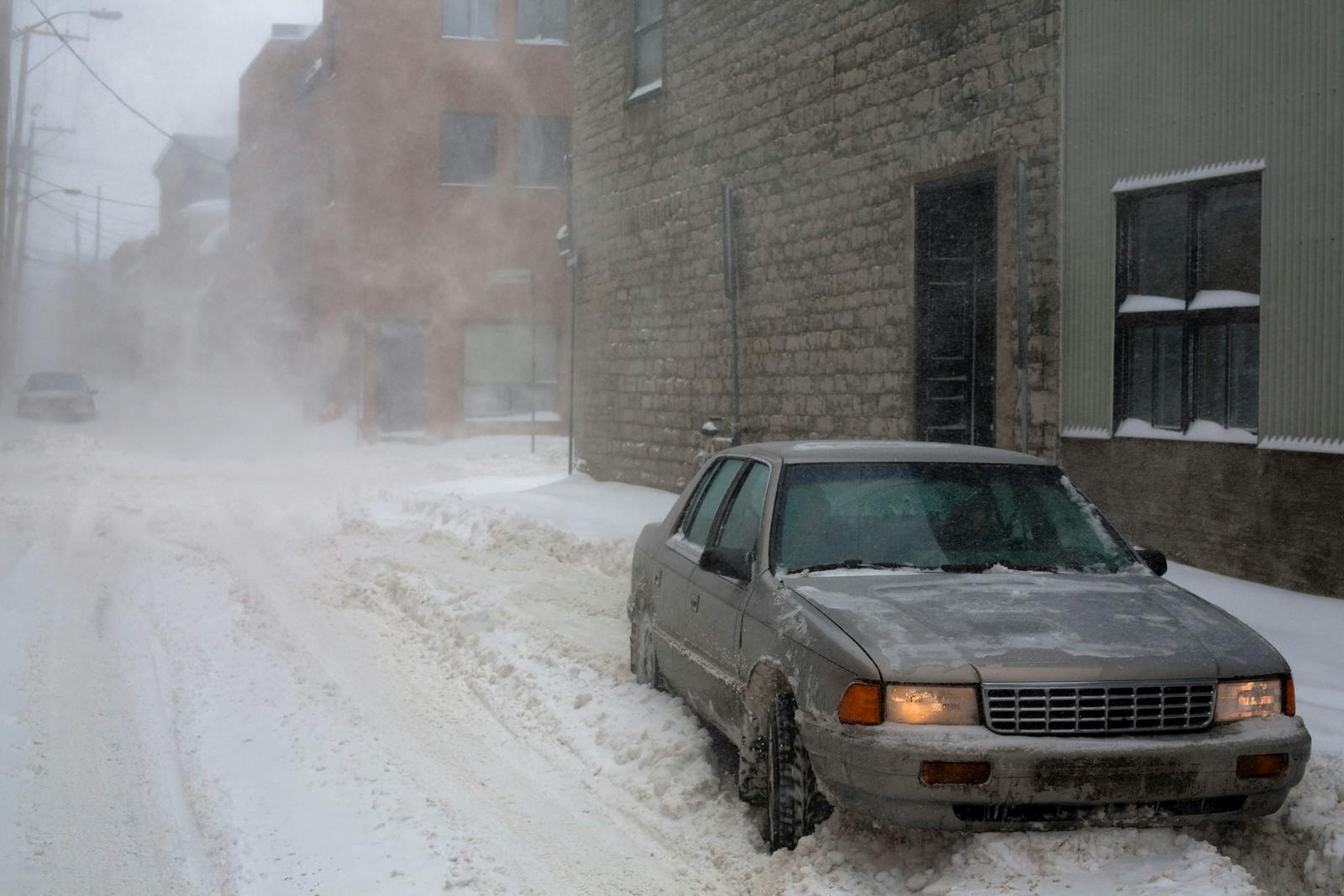 Harsh winter conditions in a snowy Quebec City street with parked cars and stone buildings.
