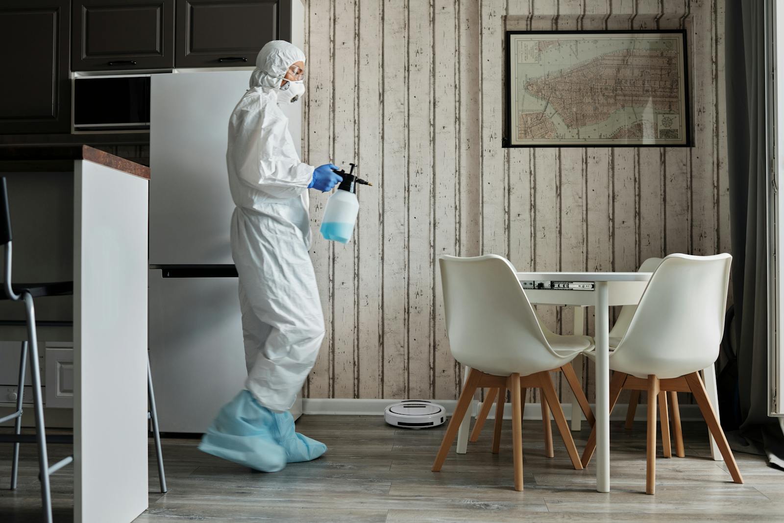 Person in protective suit using disinfectant in a contemporary living area during the COVID-19 pandemic.